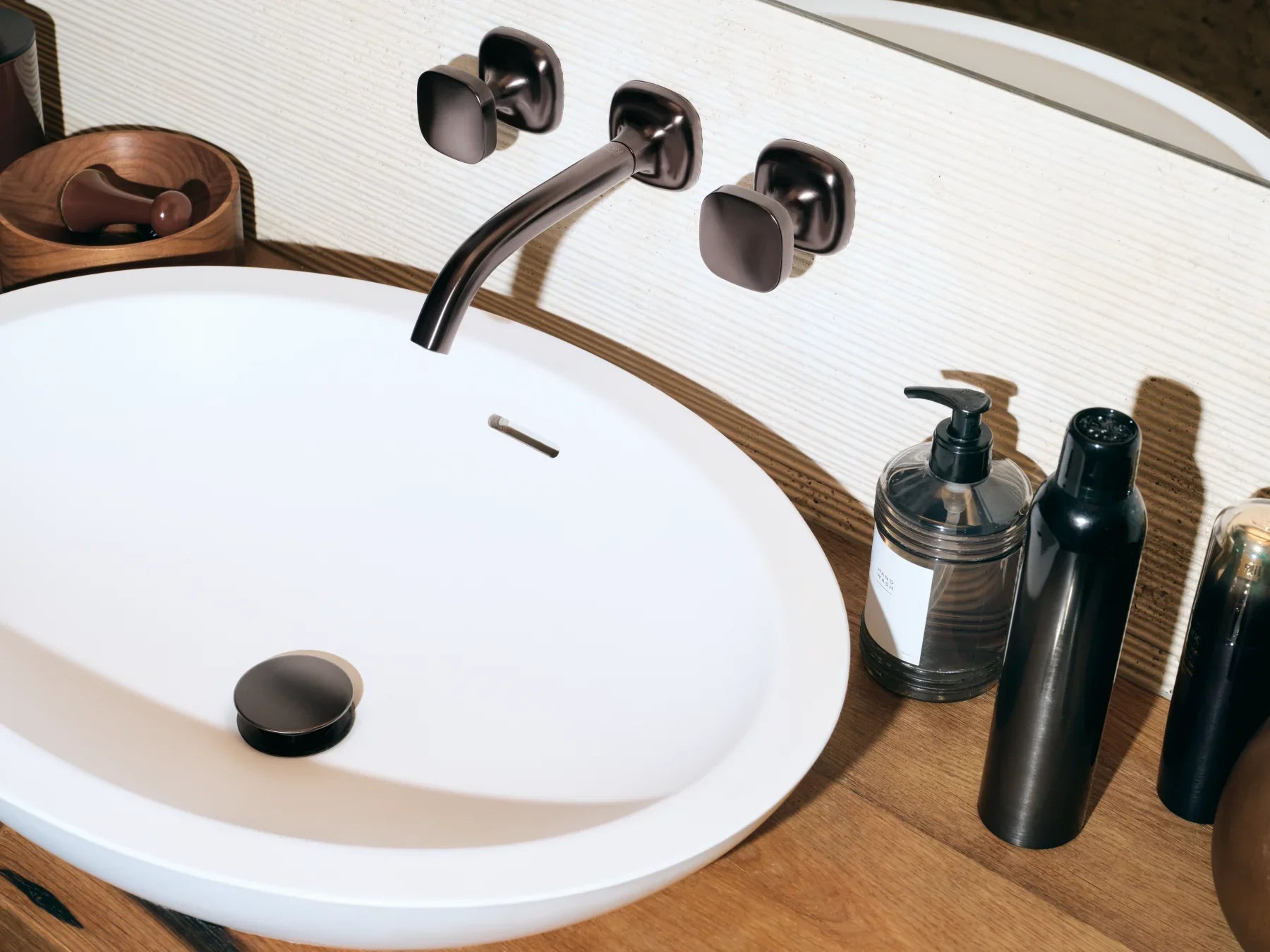 Llave de lavabo de montaje en muro sobre un lavabo ovalado blanco